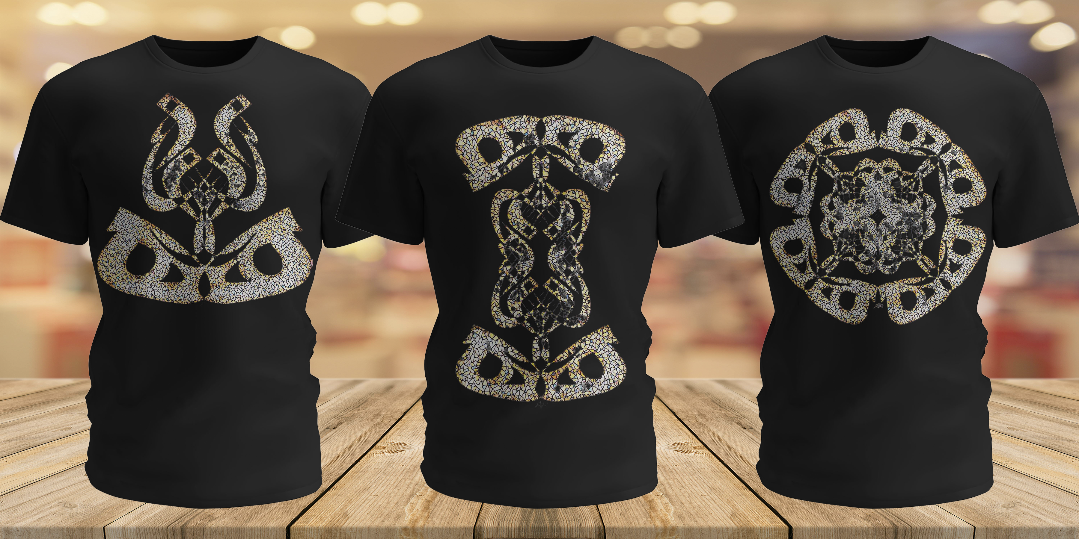 Three black t-shirts with light gold graphic designs on a wooden surface.